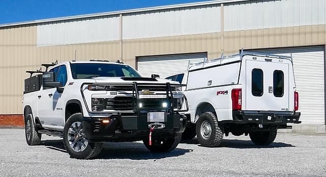 Two white work trucks equipped for commercial fleet use